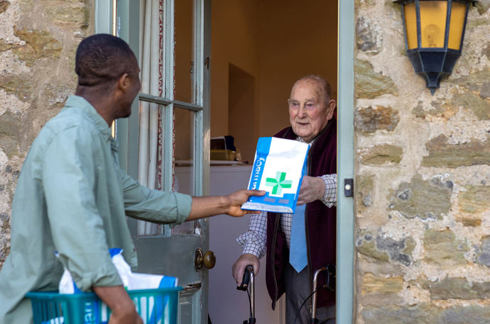 A Volunteer Responder delivering a prescription to an older man at his home
