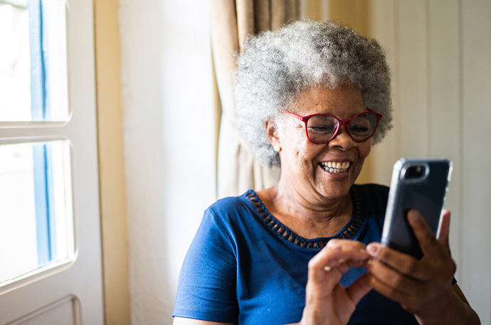 An older woman texting on her phone and smiling 